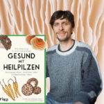 Philip Rebensburg sitzt hinter seinem Buch "Gesund mit Heilpilzen"